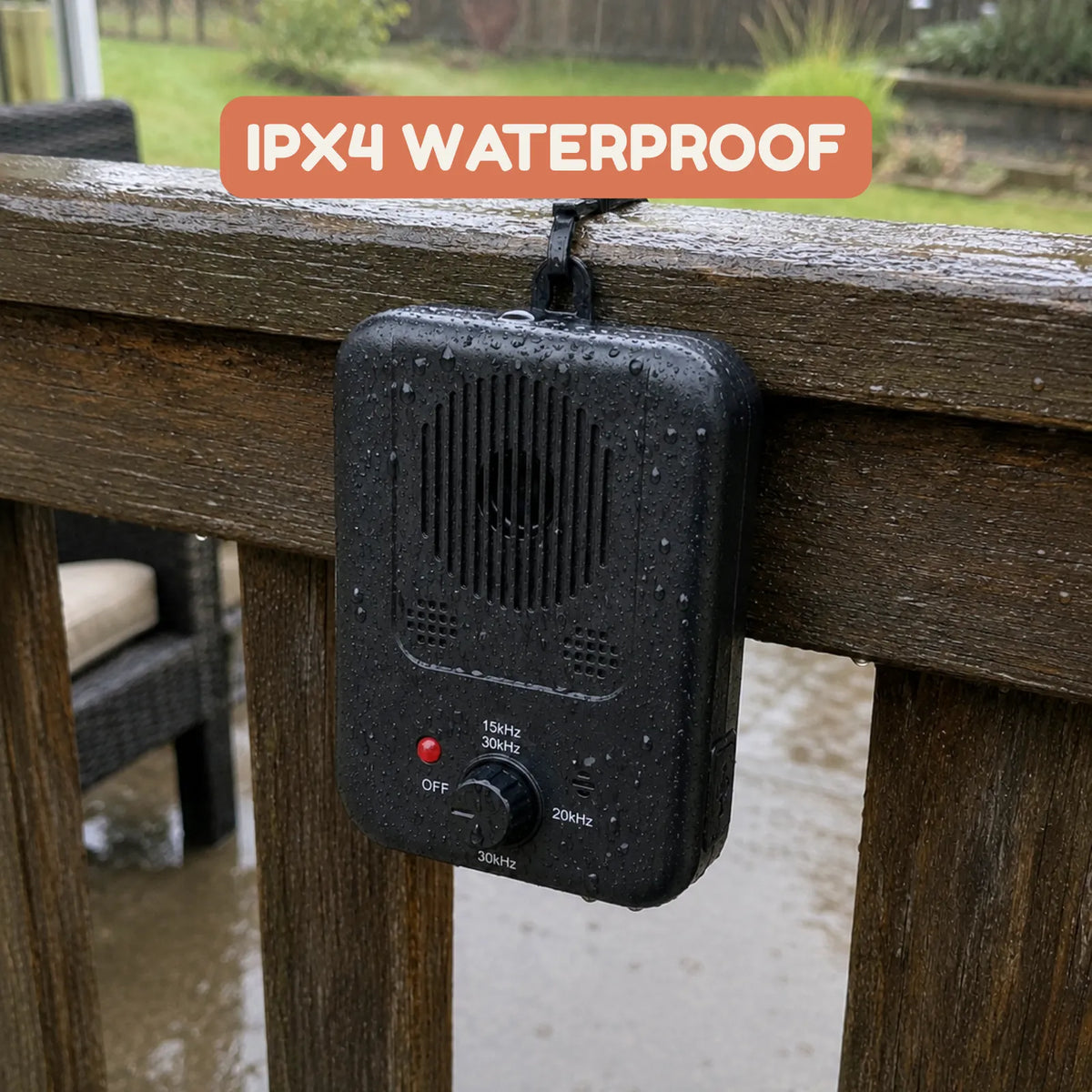 A black waterproof PupMute Bark Controller hanging from a wooden deck railing outdoors on a rainy day, with water droplets on its surface and an orange text overlay that reads 'IPX4 WATERPROOF'.